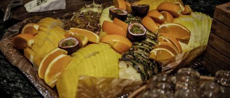 Una bandeja de frutas con diversas frutas y un plato de queso sobre una mesa.