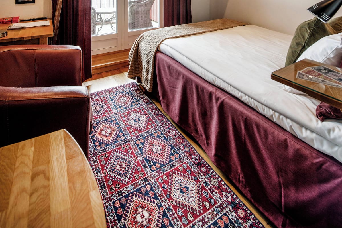 A hotel room with a bed, a desk, a chair, a TV, and a balcony with a view.