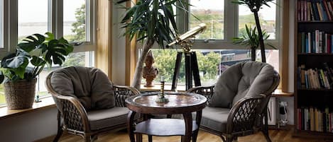 Une pièce chaleureuse avec un plancher en bois, deux fauteuils confortables, une table ronde et une bibliothèque.