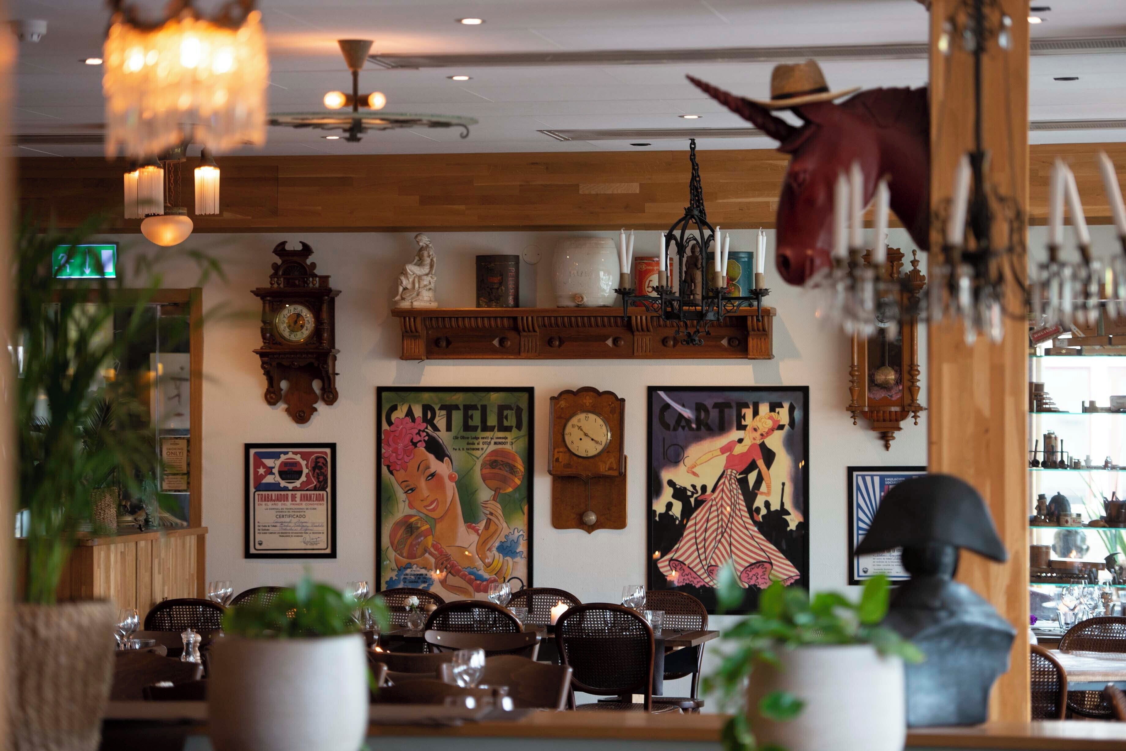 A restaurant interior with wooden paneling, a clock, vintage posters, and a mounted horse head.
