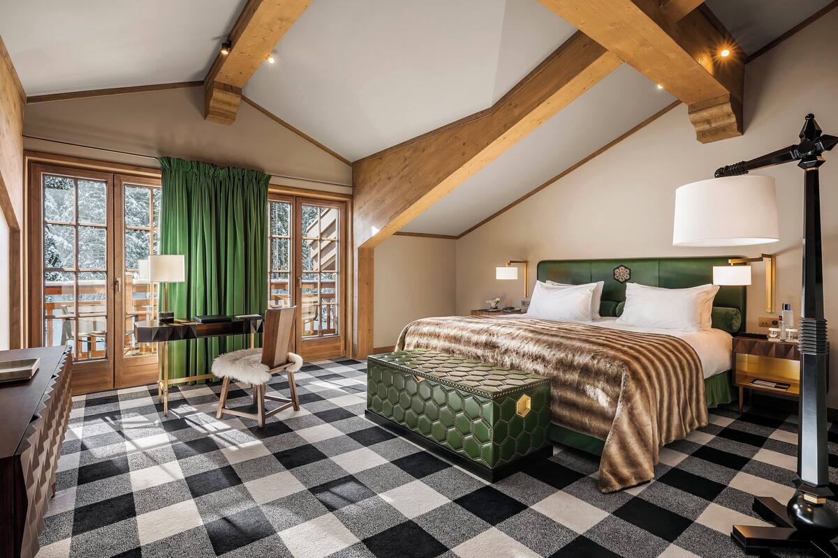 Ein Schlafzimmer mit Schachbrettfußboden, einem Bett mit grünem Kopfteil, einem Schreibtisch und einem Stuhl.