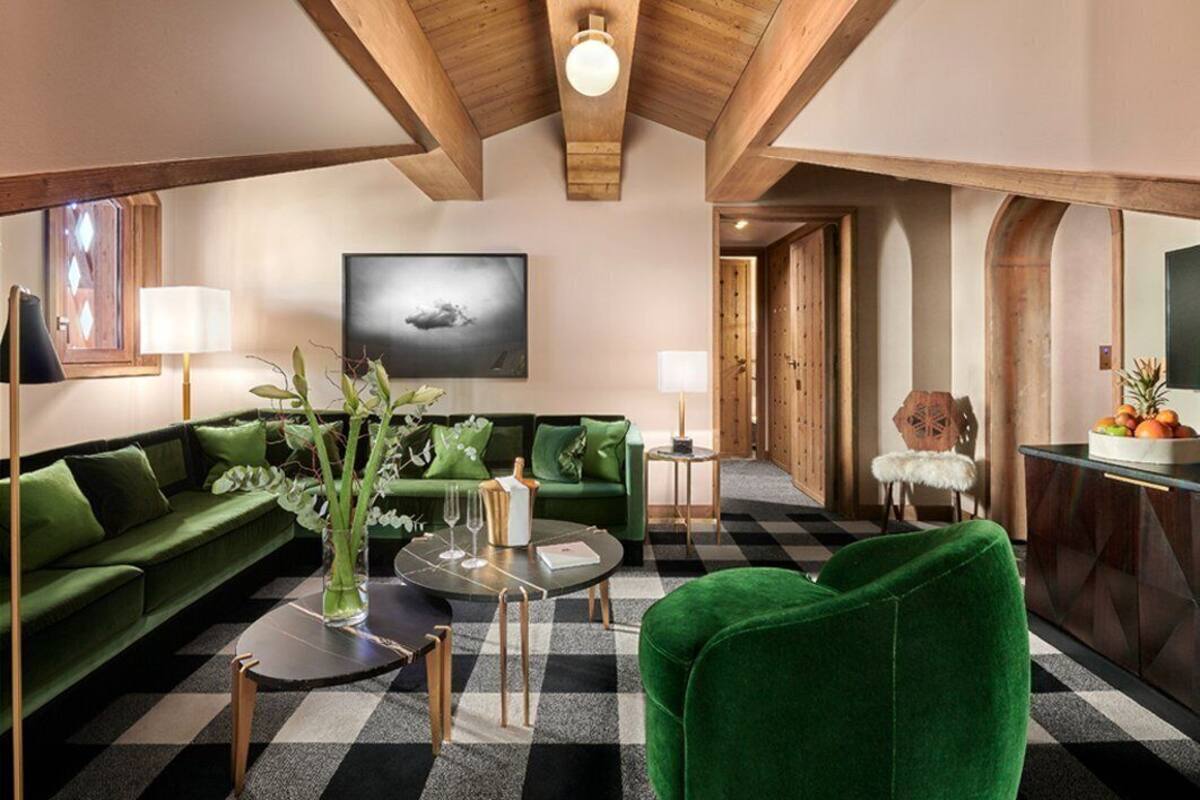 Ein modernes Wohnzimmer mit Schachbrettfußboden, grünen Sofas, einem Couchtisch und einem großen Gemälde an der Wand.