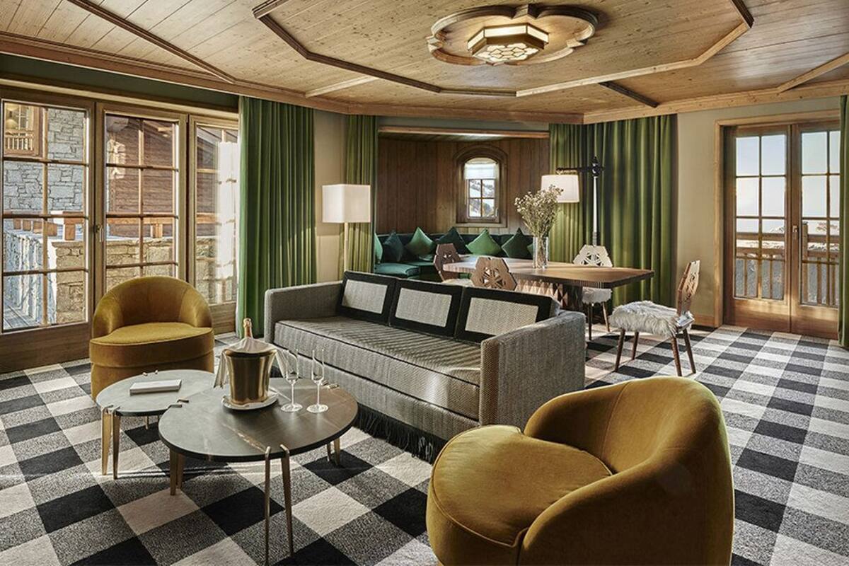 Ein gemütliches Zimmer mit Schachbrettmuster-Boden, einer Couch, zwei Sesseln, einem Tisch und einer Lampe.