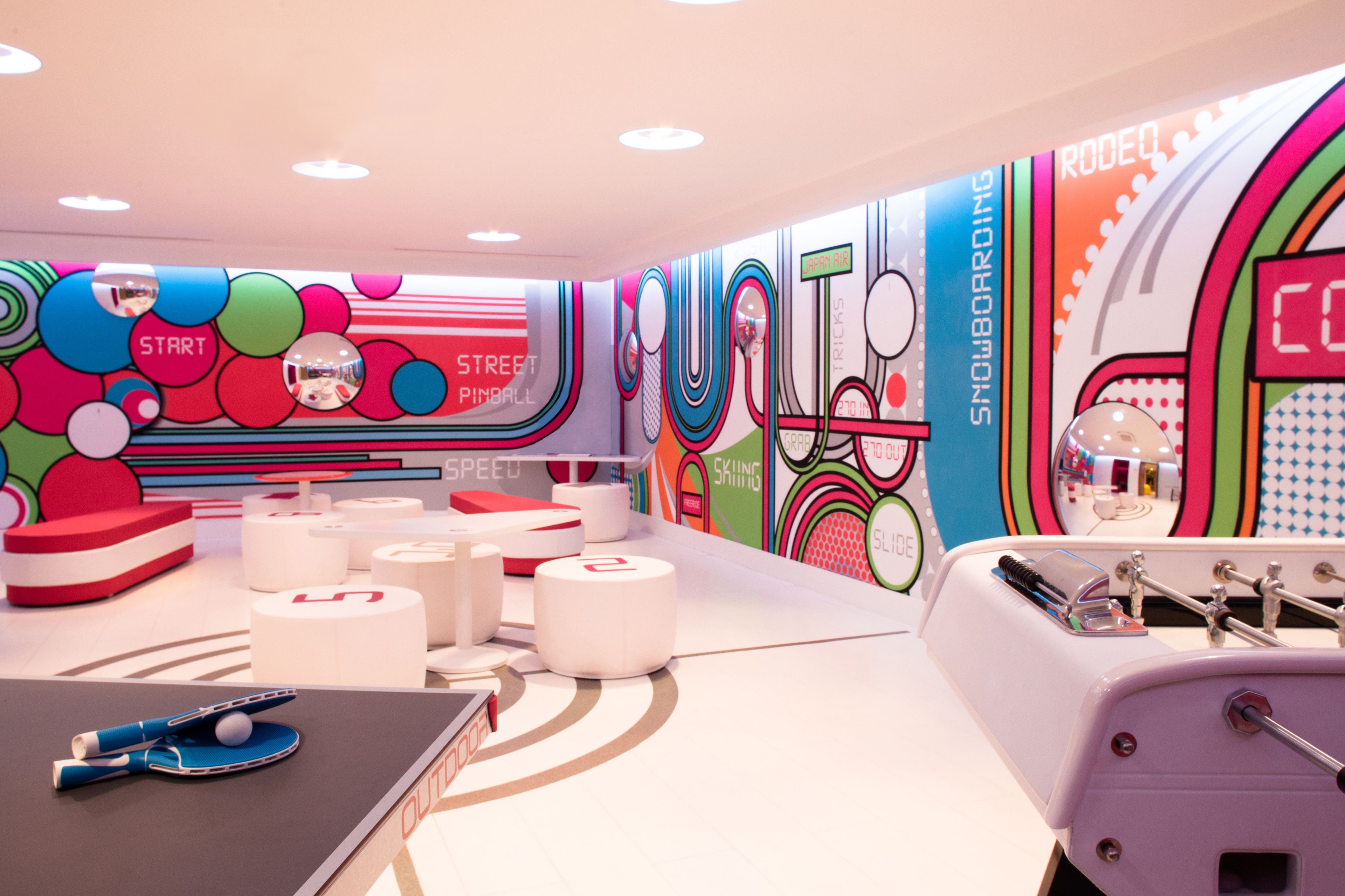 A brightly colored indoor play area with various sports equipment and a mirrored wall.