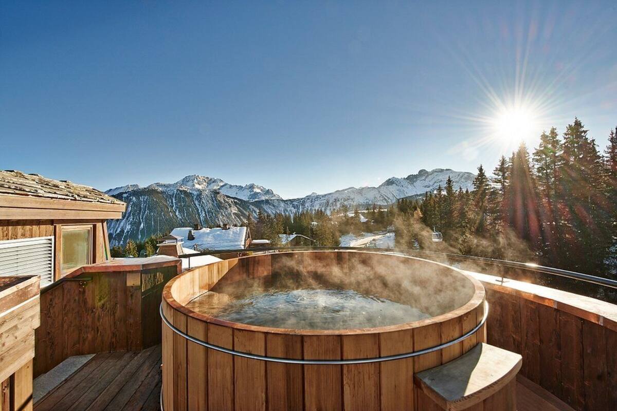 Ein hölzernes Whirlpool mit weitreichendem Bergblick, umgeben von einer Holzterrasse.