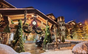 A snow-covered building with a stone tower, wooden beams, and Christmas decorations. - Apogée Courchevel, Oetker Hotels (Courchevel)