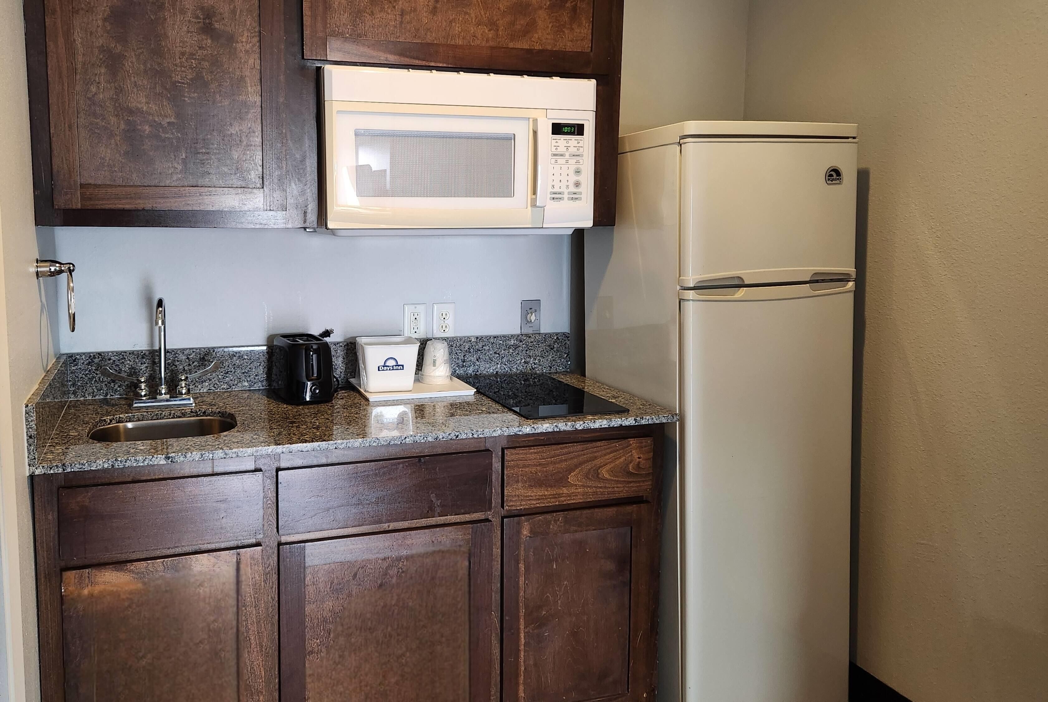 A compact kitchen with a microwave, a refrigerator, a sink, and a coffee maker.