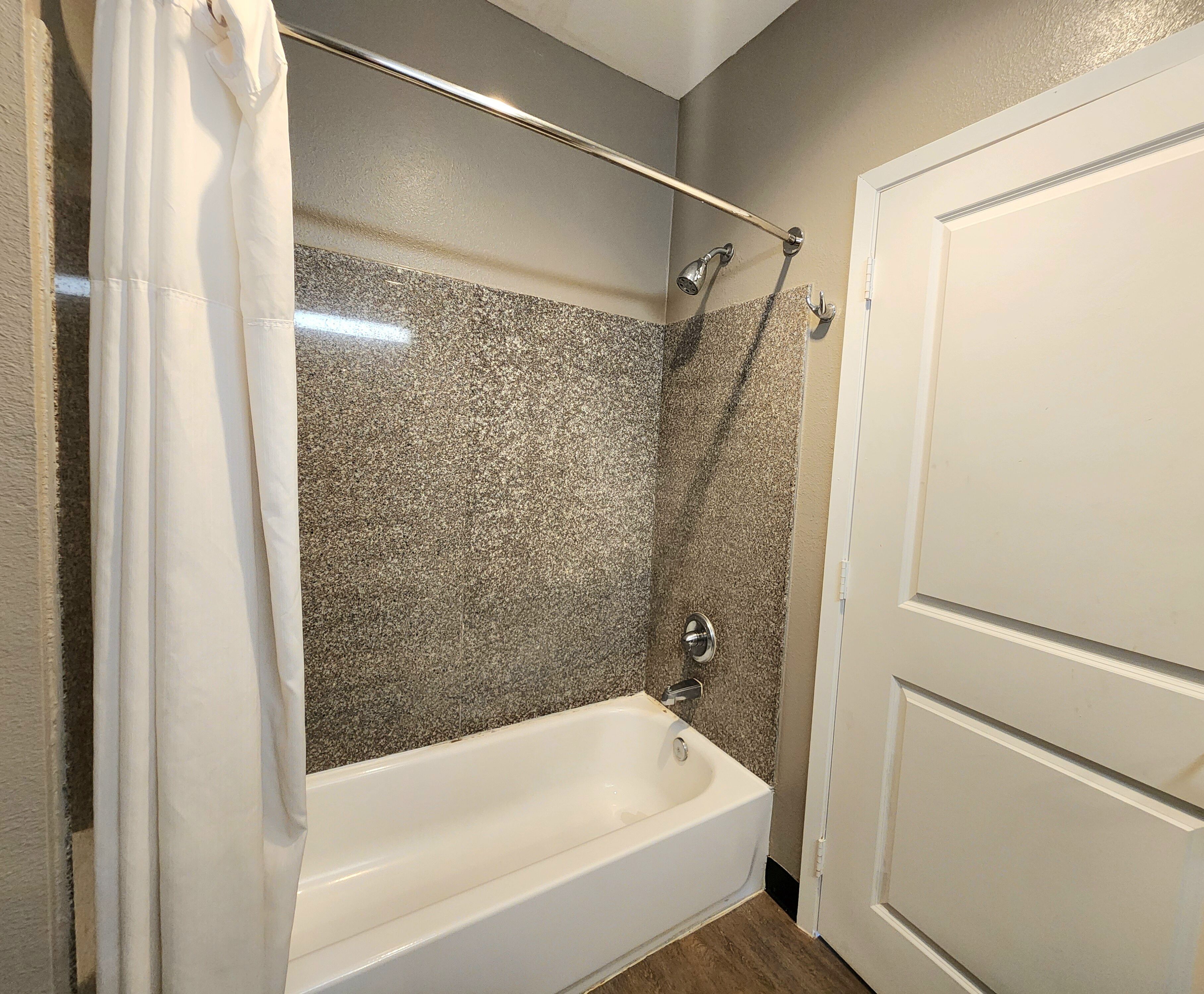 A bathroom with a bathtub, shower, and a door.
