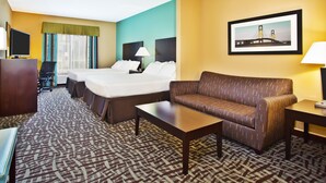 Una habitación de hotel con cama, sofá, escritorio y televisión.