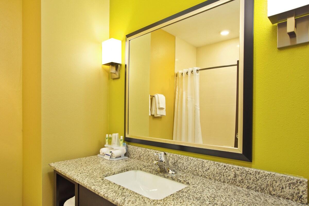 A bathroom with a granite countertop, a white sink, a mirror, and a shower curtain.