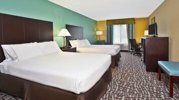 A hotel room with two beds, a desk, a chair, a television, and a window with curtains.