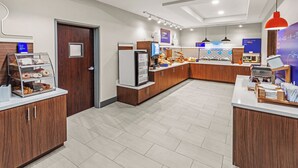 A modern breakfast area with a counter, display cases, and a digital menu board. - Holiday Inn Express & Suites San Antonio - Frost Bank Ctr (San Antonio)