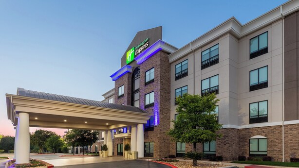 A Holiday Inn Express hotel with a covered entrance, multiple windows, and a brick facade. - Holiday Inn Express & Suites San Antonio - Frost Bank Ctr (San Antonio)