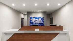 A reception area with a modern design, featuring a reception desk, a blue and white geometric wall art, and a sign indicating the hotel name. - Holiday Inn Express & Suites San Antonio - Frost Bank Ctr (San Antonio)
