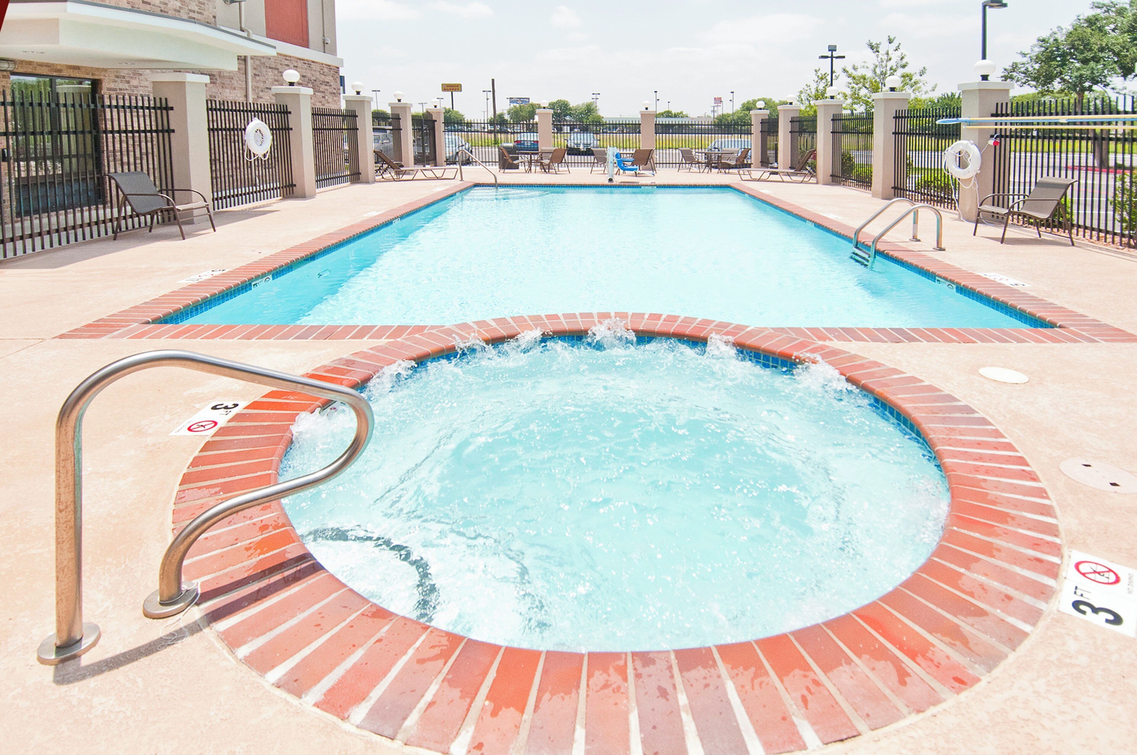 A rectangular swimming pool with a hot tub in the foreground.