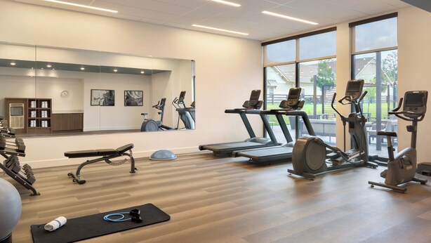 A gym with exercise equipment, a mirror, and large windows. - Staybridge Suites Atlanta Airport by IHG (Atlanta)