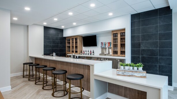 A modern kitchen with a bar area, wooden cabinets, and a tiled backsplash. - Staybridge Suites Atlanta Airport by IHG (Atlanta)