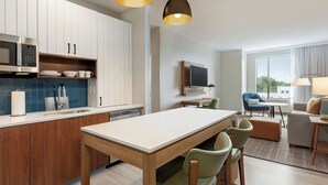 A modern kitchen with a dining area, wooden cabinets, and a flat-screen TV. - Staybridge Suites Atlanta Airport by IHG (Atlanta)