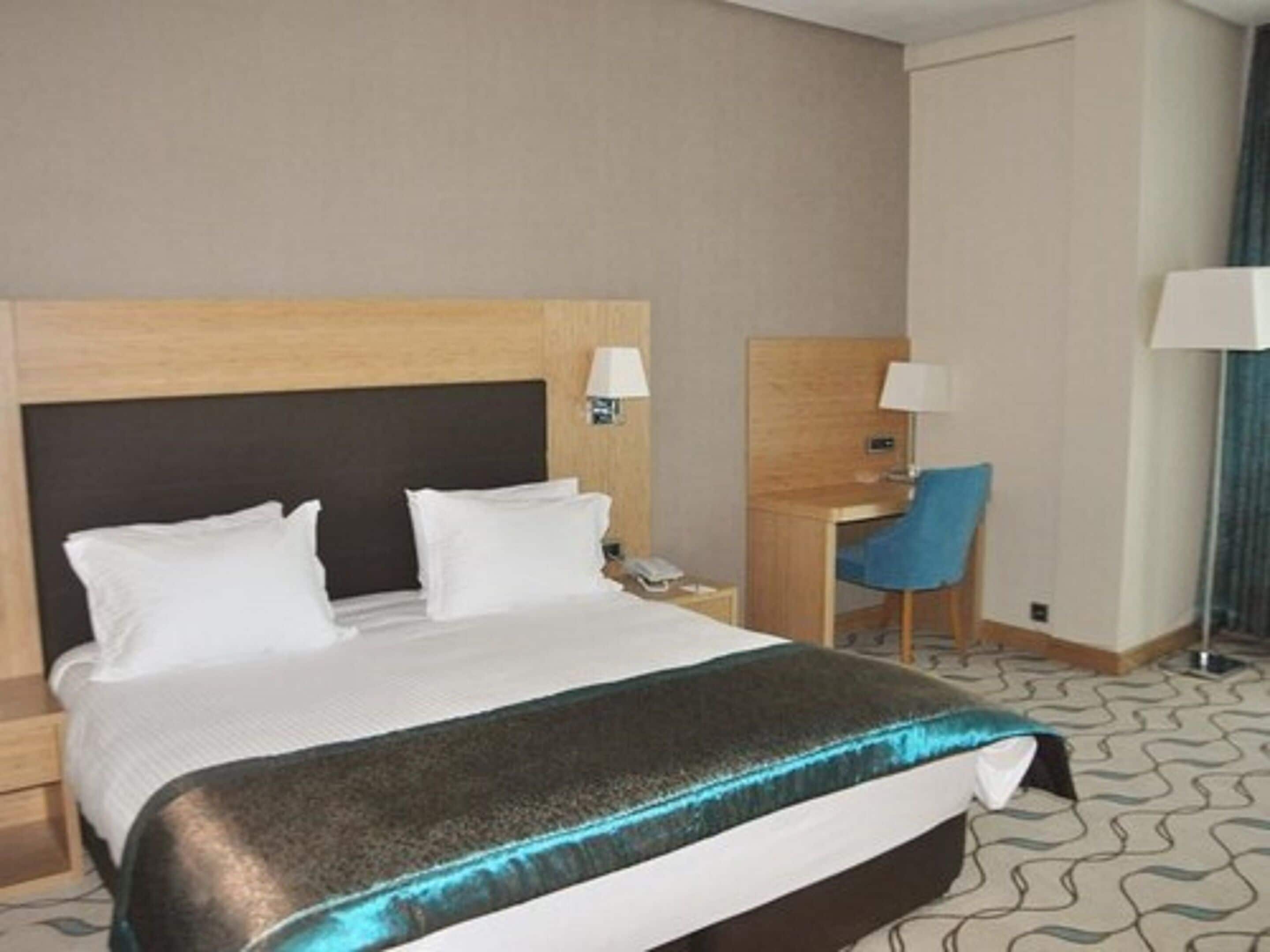 Una habitación de hotel con una cama, un escritorio y una silla.