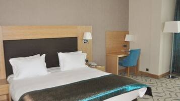 Una habitación de hotel con una cama, un escritorio y una silla.