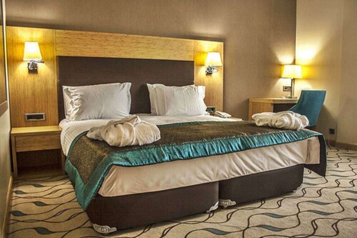 Habitación de hotel con una cama grande, dos lámparas de noche, una silla y una mesita de noche.