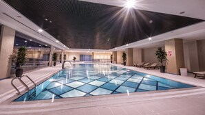 An indoor swimming pool with clear water, surrounded by lounge chairs and potted plants. - Margi Hotel (Edirne)