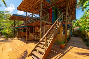 A wooden staircase leading to a multi-level wooden structure with a balcony, surrounded by lush greenery. - Pousada Canto Bravo (Ilhabela)
