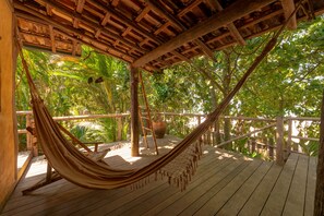 A hammock on a wooden deck with a view of lush greenery. - Pousada Canto Bravo (Ilhabela)