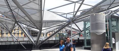 An outdoor area with a modern metal structure and a glass building in the background.