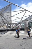 An outdoor area with a modern metal structure and a glass building in the background.