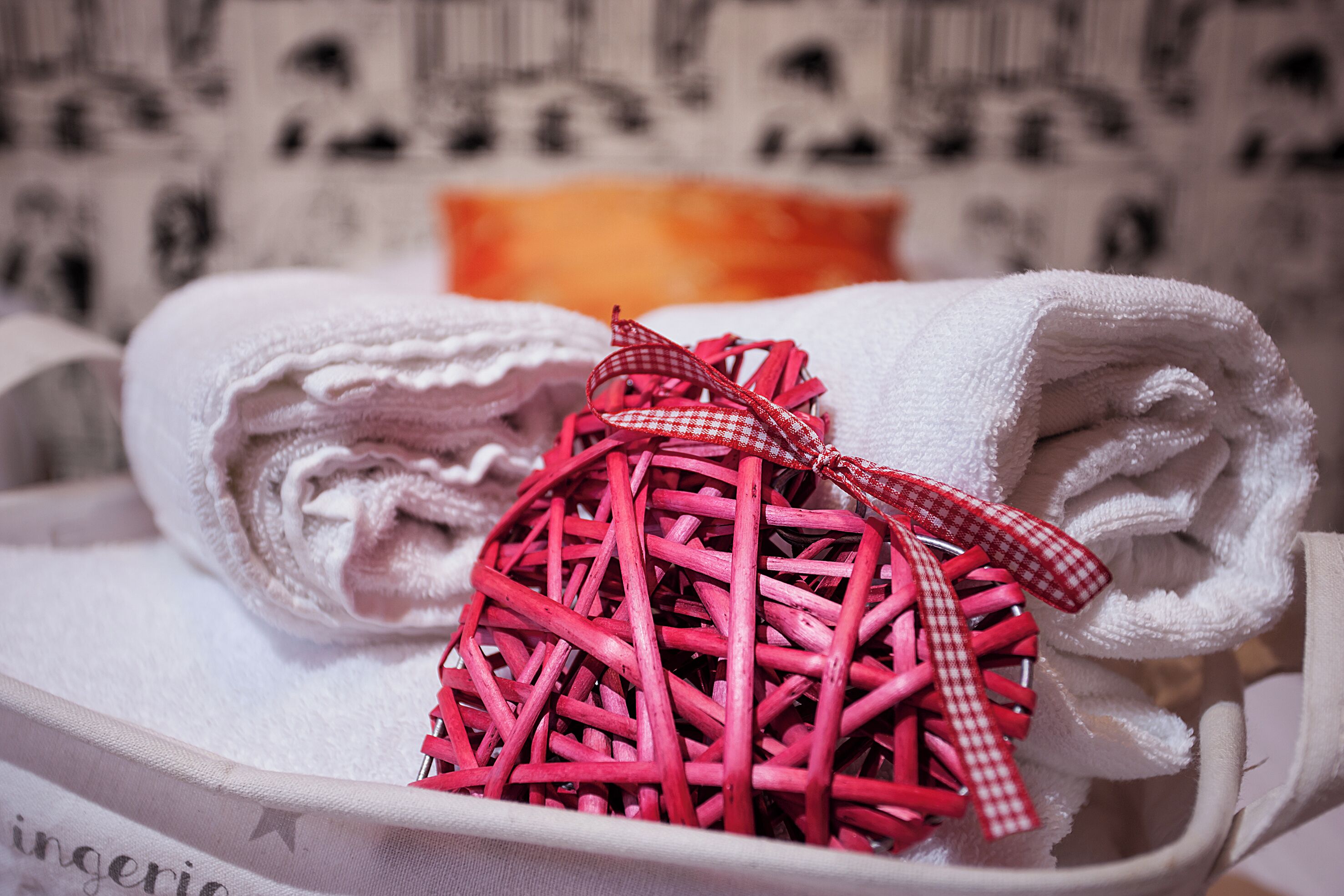 A white shoe with a red and white checkered bow and a pink woven ball.