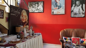A dining area with a buffet table, red walls, and framed pictures on the wall. - Hotel Cine Holiday (Naples)
