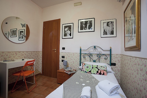 A bedroom with a bed, a desk, a chair, and a mirror. There are framed pictures on the wall. - Hotel Cine Holiday (Naples)