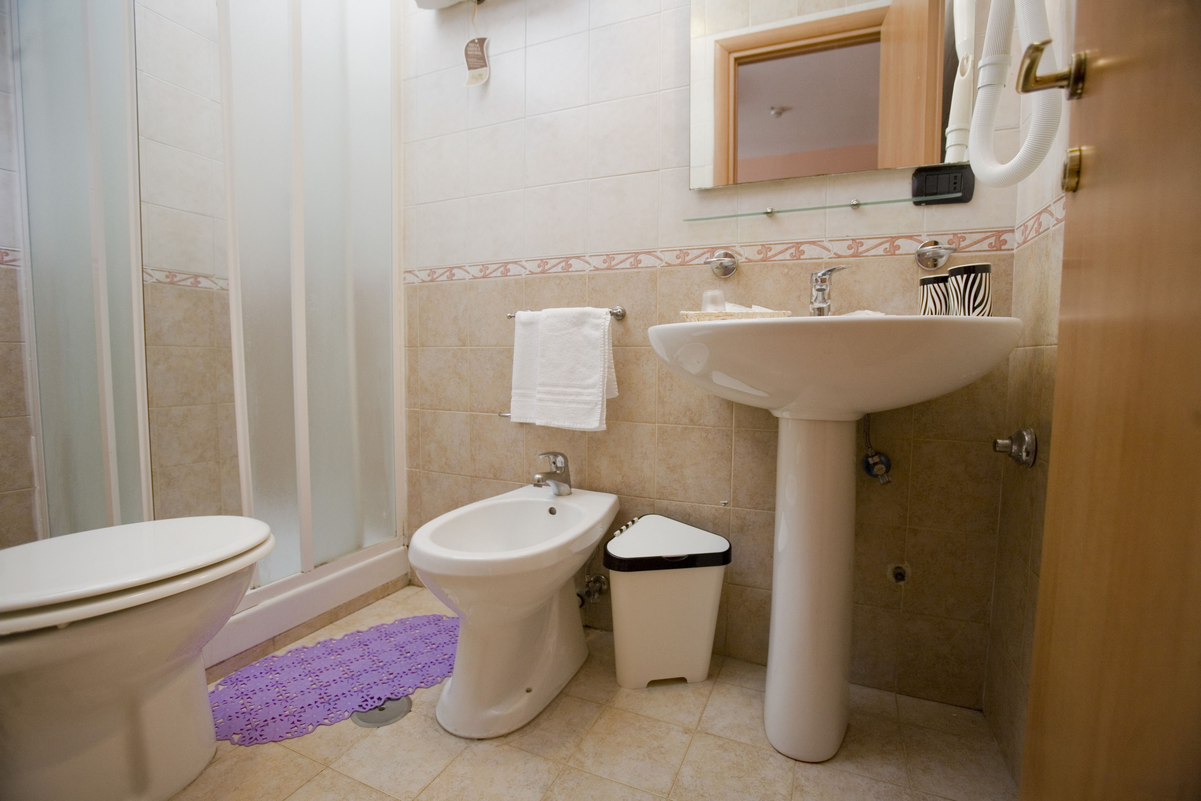 Une salle de bain comprenant des toilettes, un bidet, un lavabo et une douche à parois de verre.