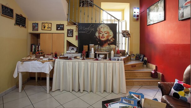 A dining area with a table set for a meal, a staircase, and various framed pictures on the walls. - Hotel Cine Holiday (Naples)
