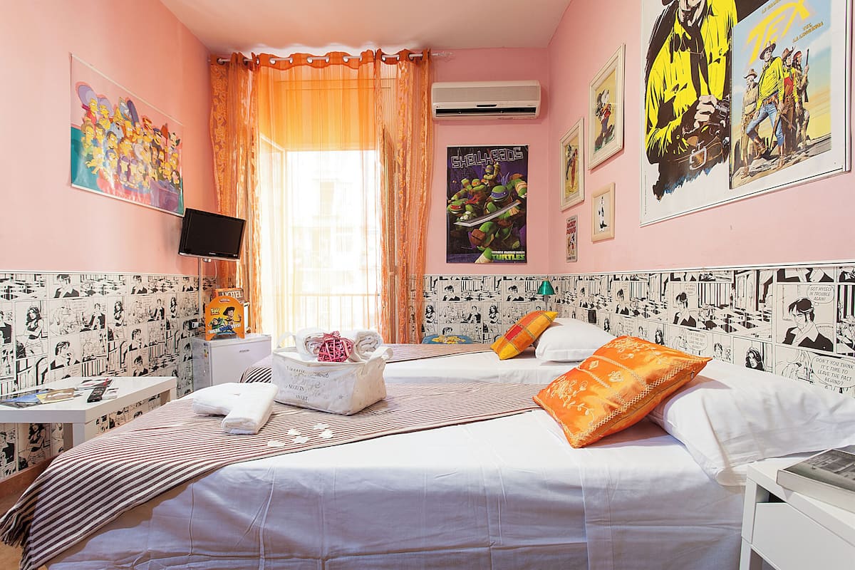 A hotel room with two beds, a TV, and a window with curtains.