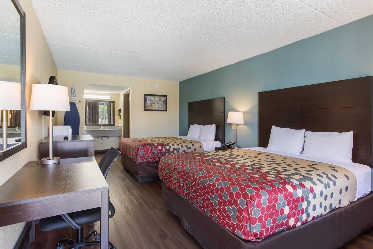 A hotel room with two beds, a desk, and a chair.