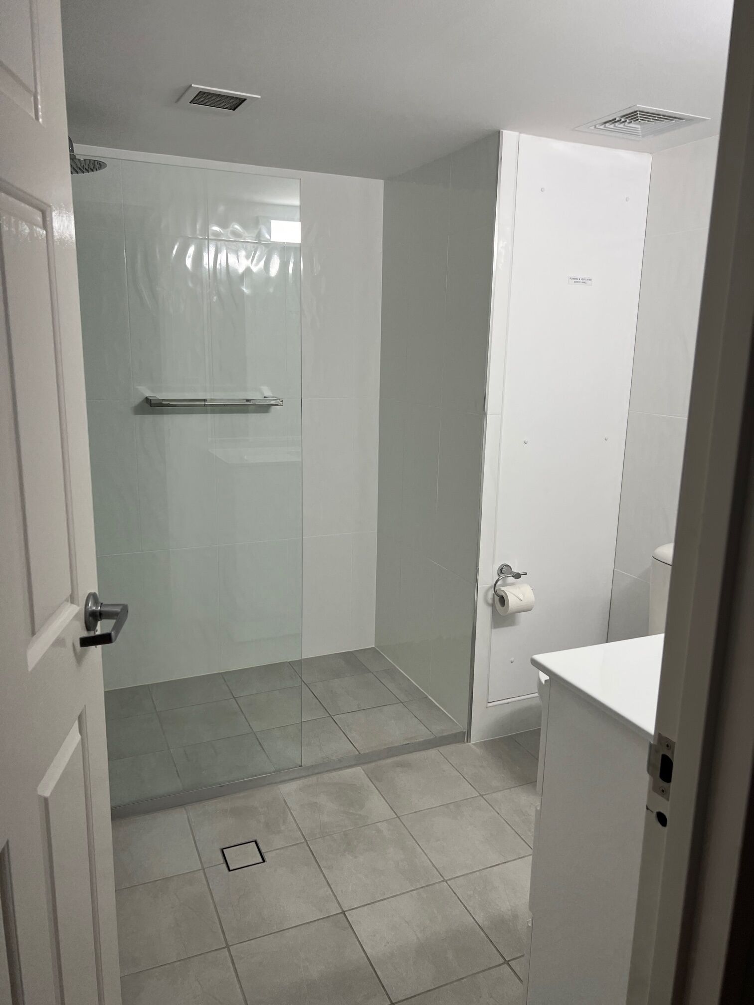 A bathroom with a glass shower enclosure, a toilet, and a sink.