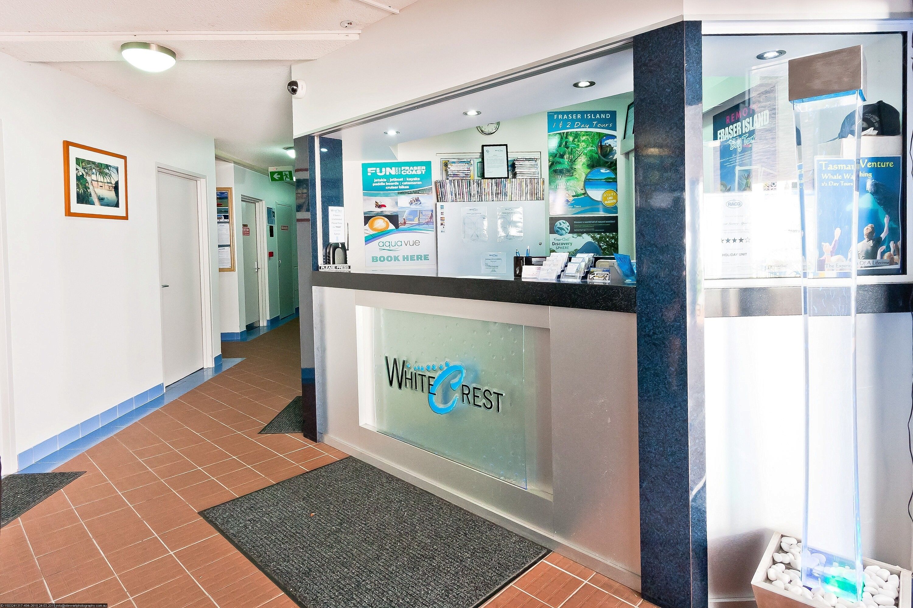 A reception area with a glass front, a sign reading "White Crest," and informational posters about local attractions.