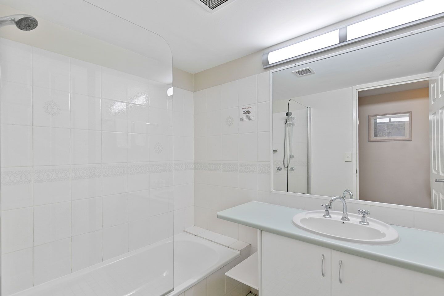 Un baño moderno con ducha envuelta en vidrio, una bañera blanca y un lavamanos con lavabo y espejo.