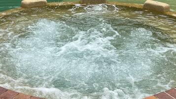 Un jacuzzi con borde de ladrillo y orilla revestida de piedras.