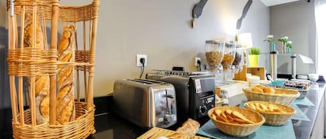 Una cocina con una cesta de mimbre para pan, dos tostadoras y una cafetera.