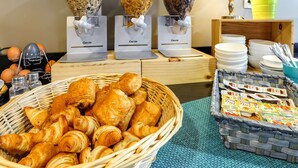 Un bufé de desayuno con croissants, granola y café.