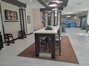 Un hall d'hôtel moderne avec une longue table à manger, des sièges et un espace d'accueil.