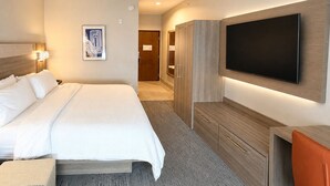 A hotel room with a bed, a flat-screen TV mounted on the wall, a wardrobe, and a desk with a chair. - Holiday Inn Express Kenedy by IHG (Kenedy)