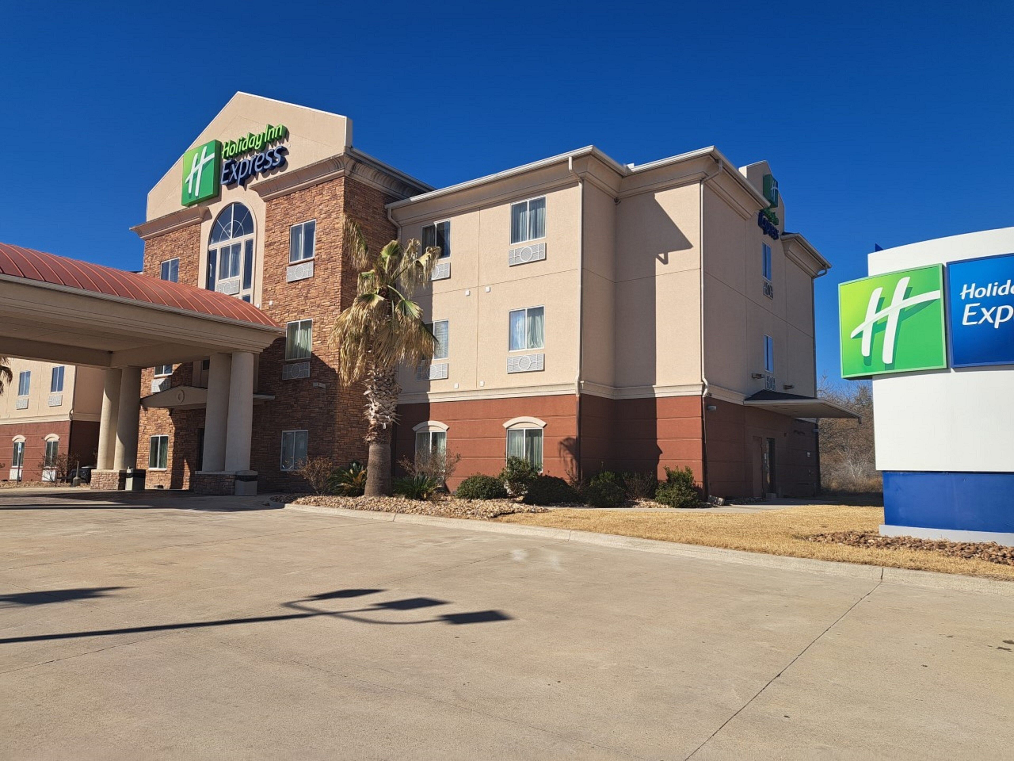 A Holiday Inn Express hotel with a brick facade, multiple windows, and a clear sky.