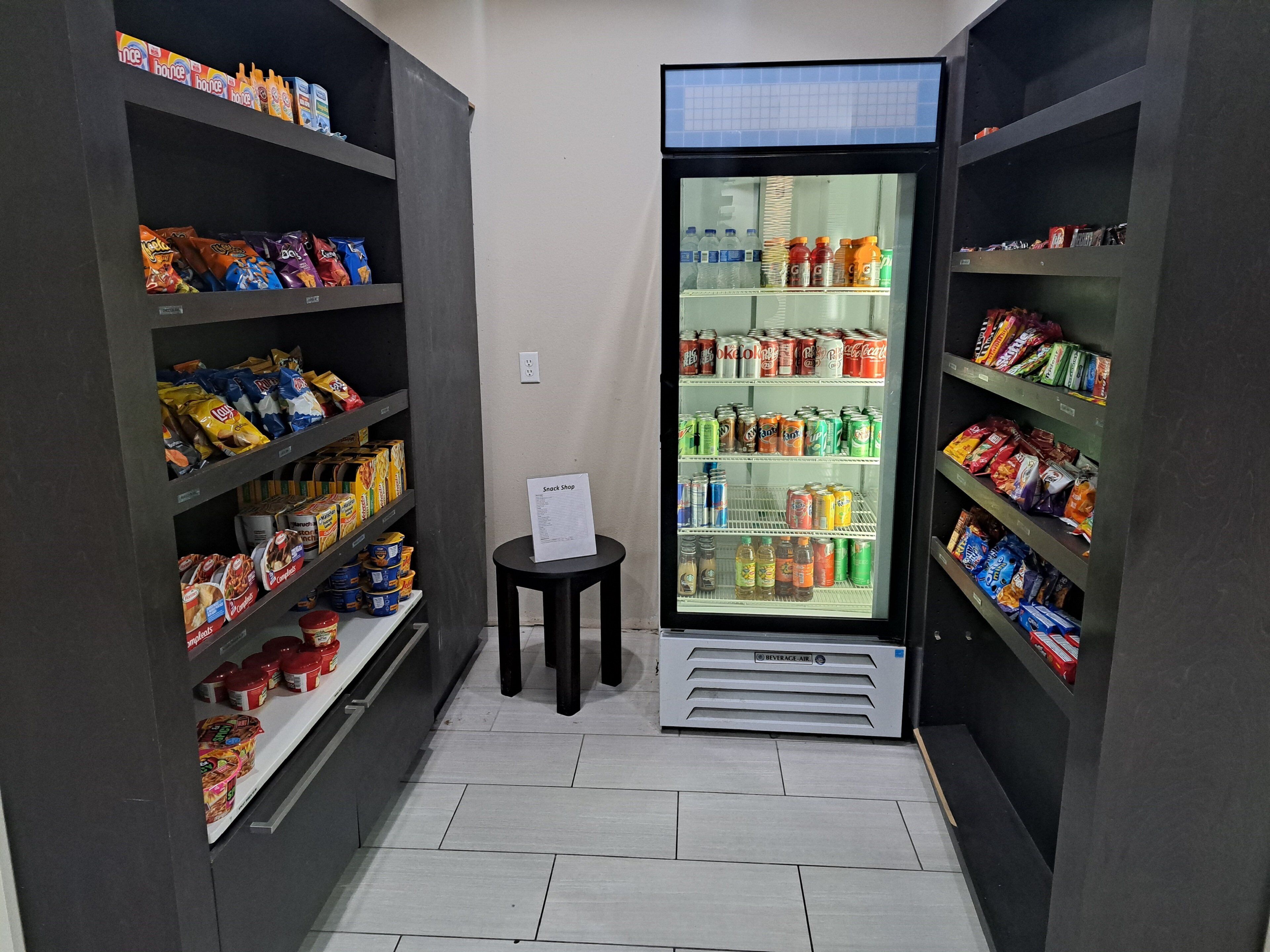 Un magasin de proximité où l’on trouve une grande variété de collations et de boissons, présentées sur des étagères bien garnies.