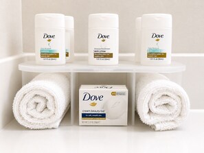 A bathroom shelf with Dove products including a shampoo, body lotion, and conditioner, and a box of Dove cream beauty bar. - Holiday Inn Express Kenedy by IHG (Kenedy)