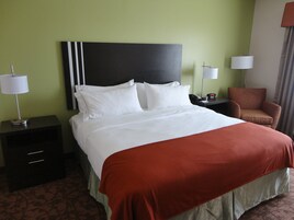 A hotel room with a bed, nightstands, a chair, and lamps.