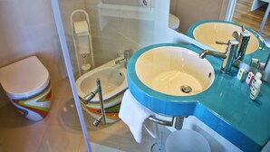 Een badkamer met twee wasbakken, een toilet en een douchecabine met glazen wanden.